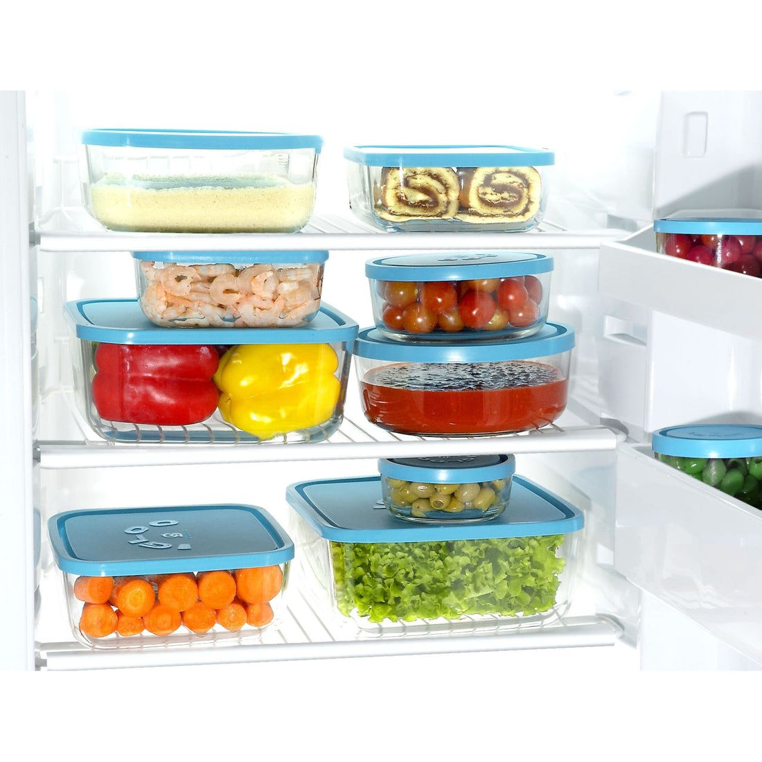 refrigerador con varios refractarios de vidrio con tapa apilados entre ellos con fruta, verdura, postres y mariscos