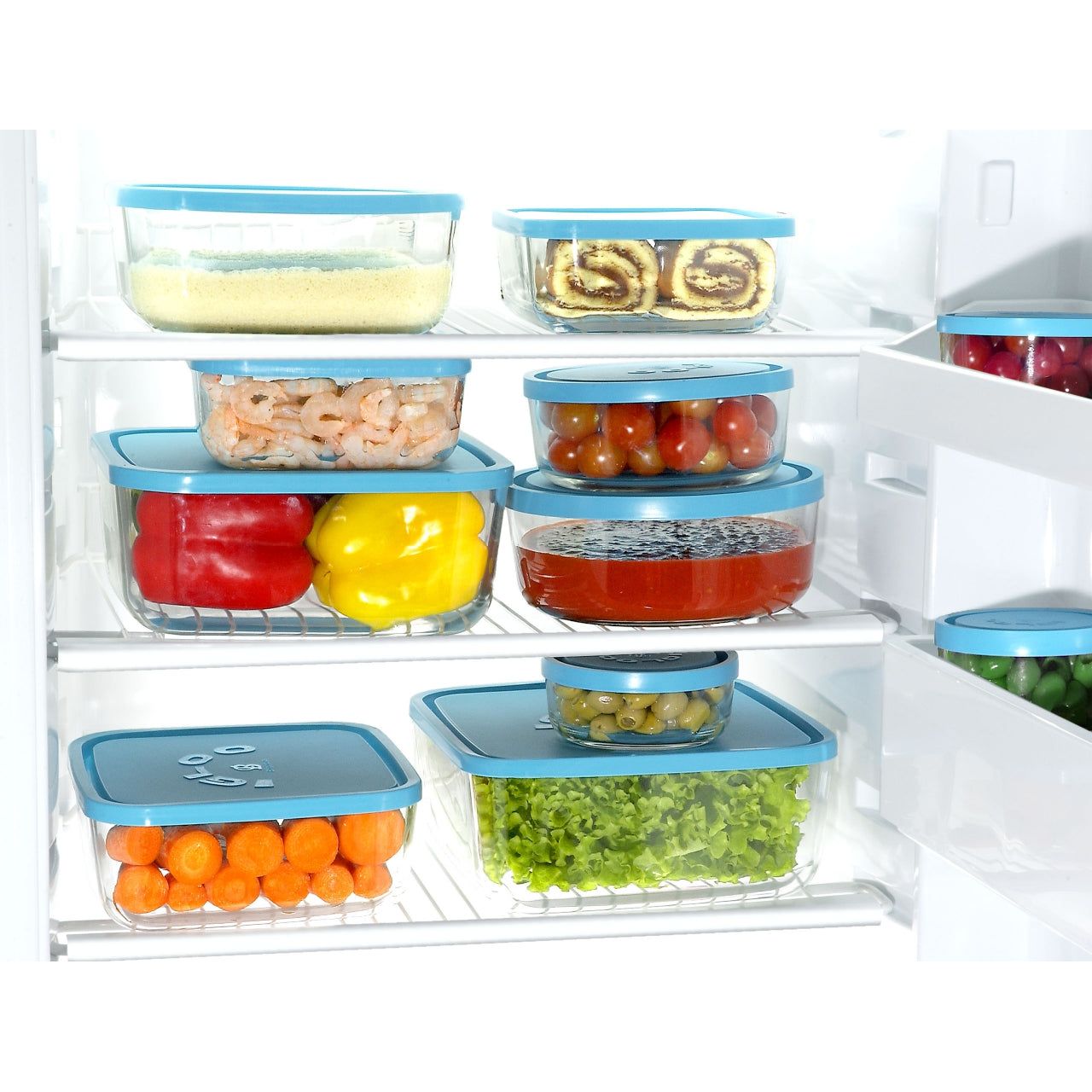 refrigerador con varios refractarios de vidrio con tapa apilados entre ellos con fruta, verdura, postres y mariscos