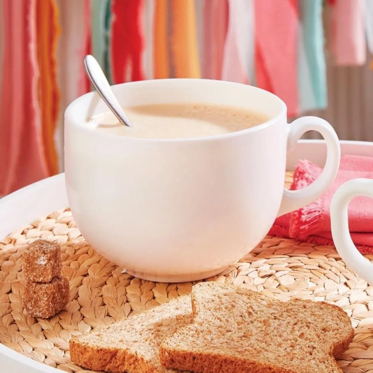 Taza jumbo blanca con café con leche sobre bandeja de desayuno, ideal para bebidas calientes.