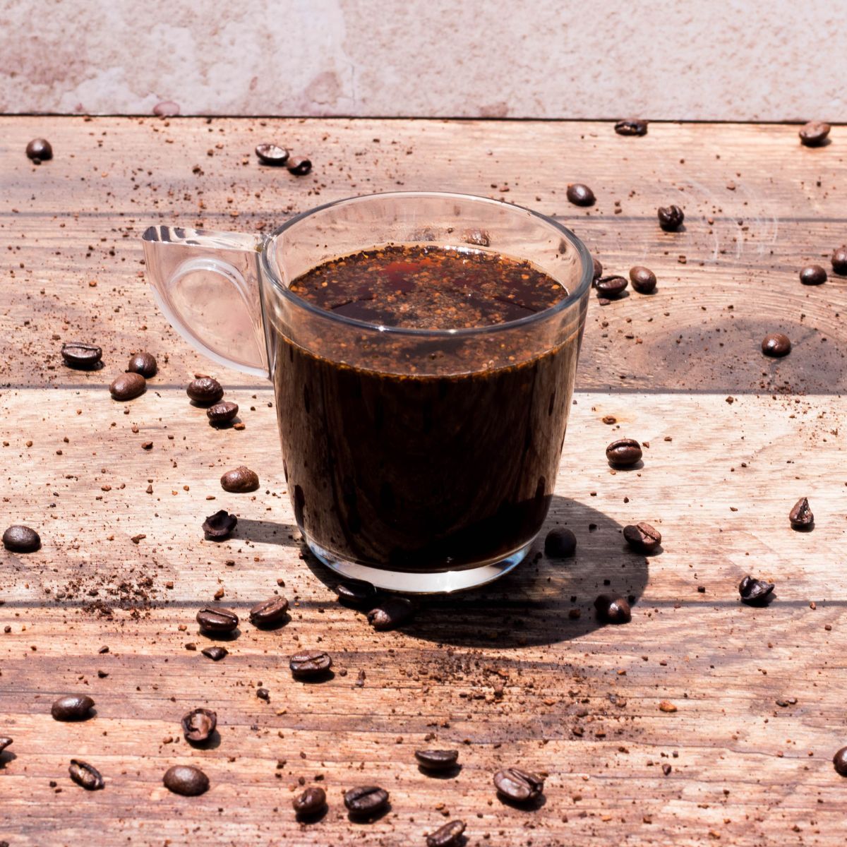Taza de vidrio Alpi con café negro servida sobre mesa rústica, ideal para cafeterías o el hogar.